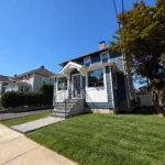 Completed exterior remodel with new blue shingle siding and front entry steps, Waltham MA