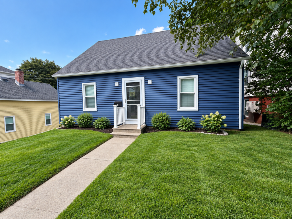 Completed home exterior with new navy vinyl siding and landscaped front lawn