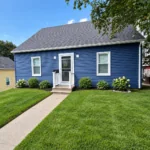 Completed home exterior with new navy vinyl siding and landscaped front lawn