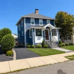 Two-story home exterior remodel with new blue siding, driveway, and landscaping