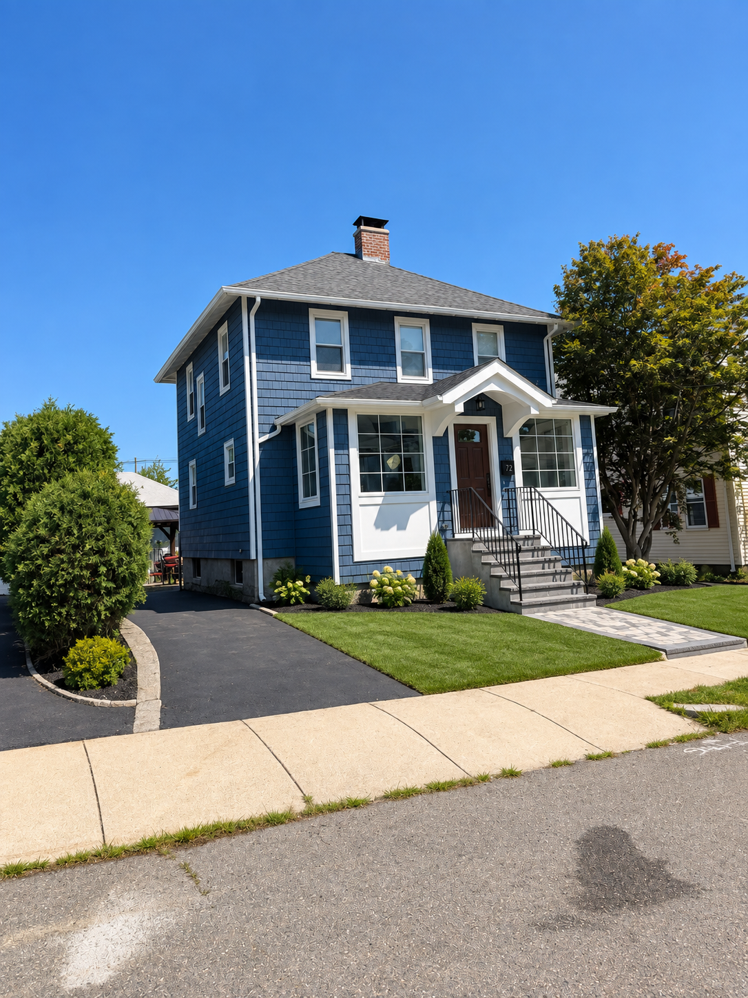 Two-story home exterior remodel with new blue siding, driveway, and landscaping